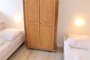 ein Schlafzimmer mit einem Holzschrank neben zwei Betten in der Unterkunft Haus Barbara - Schwimmbad und Sauna im Haus - Whg 3 in Grömitz