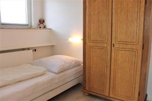 1 Schlafzimmer mit 2 Betten und einem großen Holzschrank in der Unterkunft Haus Barbara - Schwimmbad und Sauna im Haus - Whg 3 in Grömitz + 3 Fotos