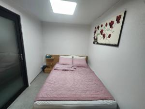 une chambre avec un lit avec une couverture rose dans l'établissement stc 1, à Séoul
