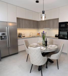 a kitchen with a table and chairs and a refrigerator at New luxury air-conditioned apartment, with jacuzzi, free parking and gardens in Pula