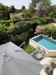 an umbrella and chairs next to a swimming pool at Villa piscine plein sud proche Uzes in Arpaillargues-et-Aureillac