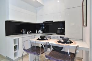 a kitchen with white cabinets and a table with chairs at Luxury one bedroom apartment in beachfront apart Hotel in Budva +6 photos