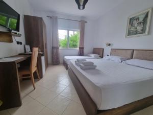 een slaapkamer met 2 bedden, een bureau en een televisie bij HOTEL VILA TWIX in Berat