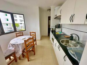une cuisine avec une table et un évier et une table et des chaises dans l'établissement Sunny Apartment, à Puerto del Carmen