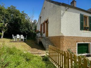 ein Haus mit einem Zaun, einem Tisch und Stühlen in der Unterkunft Charmante maison in Joux-la-Ville