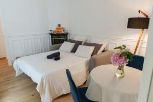 dwa łóżka w pokoju z dwoma stołami i kwiatami w obiekcie Le Marais cosy-comfy appartment w Paryżu