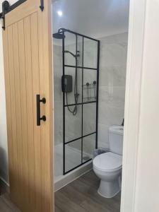 a bathroom with a toilet and a glass shower door at The Old Stable, Rustic Charm Modern Comforts in Gorfield
