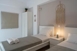 a white bedroom with two beds and a night stand at Valia's Place in Tsoutsouros