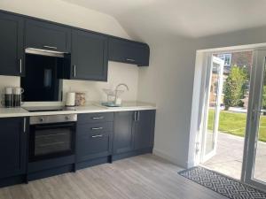a kitchen with black cabinets and an open door at The Old Stable, Rustic Charm Modern Comforts in Gorfield