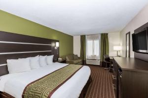 a hotel room with a bed and a flat screen tv at Baymont by Wyndham Louisville South/Shepherdsville/I 65 in Brooks +18 photos