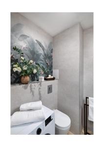 a bathroom with a toilet and a painting on the wall at Amber Premium Apartments in Bydgoszcz +49 photos
