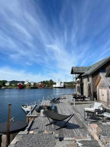 a dock with chairs and tables on the water at Amundøya Penthouse in Kristiansund