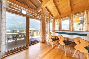 une salle à manger avec une table et des chaises et une grande fenêtre dans l'établissement Schöneben Chalet Enzian, à Wald im Pinzgau