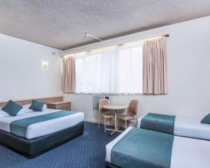 a hotel room with two beds and a table at Comfort Inn Regal Park in Adelaide