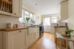 Il comprend une grande cuisine avec des placards blancs et du parquet. dans l'établissement Forest Cottage, à Lymington 37 autres photos
