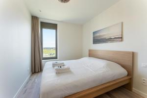 オーステンデにあるLichtrijk en ruim appartement met zeezicht - 5pの大きなベッドと窓のある白い寝室