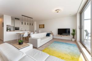オーステンデにあるLichtrijk en ruim appartement met zeezicht - 5pの白い家具と大きな窓のあるリビングルーム