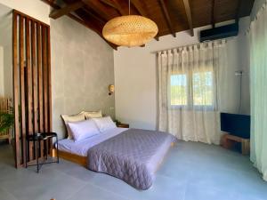 a bedroom with a bed and a large window at Akasti Slow Living in Paralia Sikias