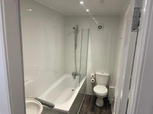 a white bathroom with a tub and a toilet at Elder Park Apartments in Glasgow +80 photos