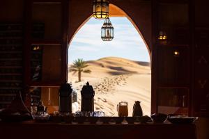 a table with a view of the desert through a window at Kanz Erremal in Merzouga