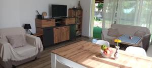 a living room with a table and a tv at Стаи за гости Пансионът на Роуз Вълшебната ми Кръстница in Chernomorets