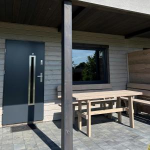 a wooden picnic table with a blue door on a porch at Stumilowy Las - Białe Domki in Mielenko