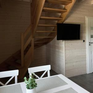 a living room with a staircase and a television at Stumilowy Las - Białe Domki in Mielenko