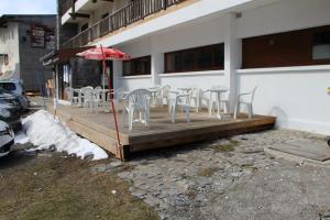 eine Holzterrasse mit Stühlen und einem Sonnenschirm in der Unterkunft Le Pourquoi Pas in Saint-Lary-Soulan