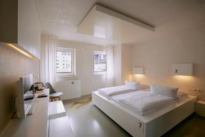 ein weißes Schlafzimmer mit einem großen Bett und einem Schreibtisch in der Unterkunft 18Arts Hotel - Living in a Gallery! in Köln