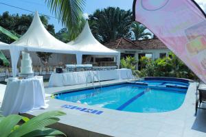 een zwembad met twee witte tenten en een zwembad bij Mowicribs Hotel and Spa in Entebbe