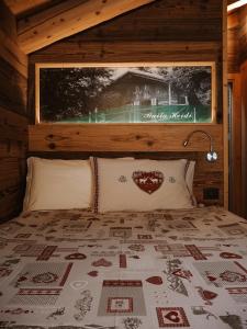 a bed in a wooden cabin with a large window at Locanda La Baita in Santo Stefano di Cadore