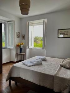 a white bedroom with a bed and two windows at Torre Galli-Dimora di Campagna in Gasponi