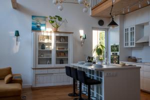 a kitchen with white cabinets and a island with chairs at Leo House in Gdynia