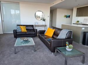 Una sala de estar con un sofá de cuero y una mesa. en Grand 2BR between ANU and City - Hosted by Canstay, en Canberra