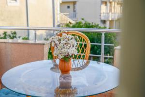 a vase with flowers sitting on a glass table at Rexha Apartments in Ulcinj