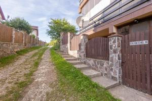 a fence next to a dirt road next to a building at Walter Home Bușteni with Private Terrace in Buşteni