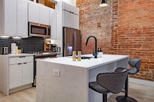 a kitchen with a white counter and a brick wall at Vibrant 2-BR Luxe Flat Adjacent Eastern Market Walk to METRO Barracks Row Capitol Hill in Washington, D.C.