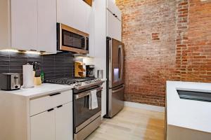 a kitchen with white cabinets and a brick wall at Vibrant 2-BR Luxe Flat Adjacent Eastern Market Walk to METRO Barracks Row Capitol Hill in Washington, D.C. +11 photos