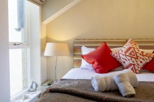 a bedroom with a bed with red and white pillows at Northern Hideaways, Seascape in Seahouses