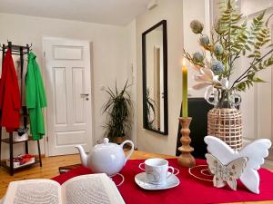 a table with a red table cloth with a tea pot and a book at Schöne Ferienwohnung am Mathildenbrunnen in Quedlinburg