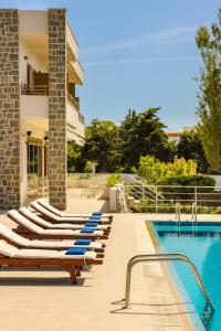 a pool with lounge chairs next to a building at Niki Beach Hotel in Kamariotissa
