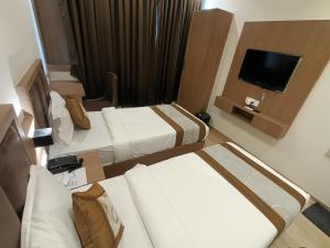 a hotel room with two beds and a flat screen tv at Hotel Beverly Palace Santacruz - Near BKC - Mumbai Airport T1 in Mumbai +34 photos