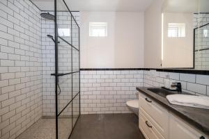a white tiled bathroom with a shower and a toilet at Family apartment hosted by LL in Akureyri +17 photos