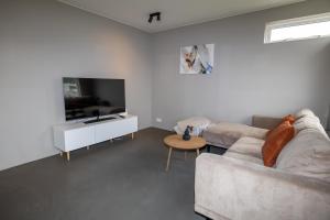 a living room with a couch and a tv at Family apartment hosted by LL in Akureyri