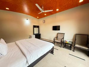 a bedroom with a white bed and two chairs at Millat Guest House F10-4 in Islamabad