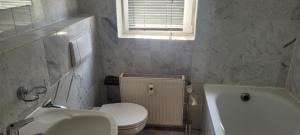a bathroom with a toilet and a sink and a tub at Schöne gemütliche Wohnung in Meerbusch