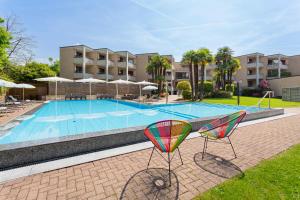 a swimming pool with two chairs in front of a building at Resort Al Centro in Breganzona