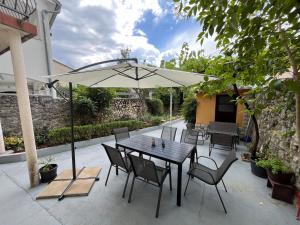 a table and chairs with an umbrella on a patio at Holliday house Kloštar in Jadranovo