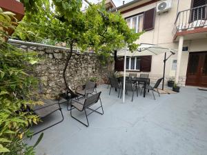 a patio with chairs and a table and a tree at Holliday house Kloštar in Jadranovo