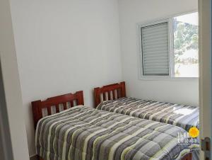 two beds sitting next to each other in a bedroom at Espaçoso, bem equipado AR e piscina Climatizada in Ubatuba +56 photos